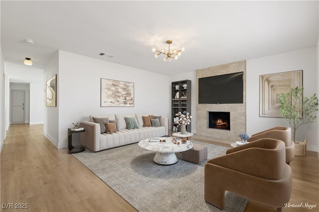 4450 San Rafael Ave, Las Vegas, NV 89120 - living room with wood finished floors, a chandelier, a tiled fireplace, built in shelves, and baseboards