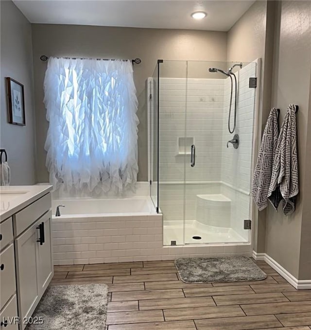 1267 Dorado Sea Ct, Henderson, NV 89052 - full bathroom featuring vanity, a stall shower, a garden tub, wood finished floors, and baseboards