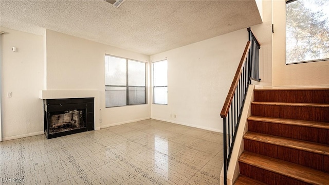 stairs with a textured ceiling, a fireplace, and baseboards
