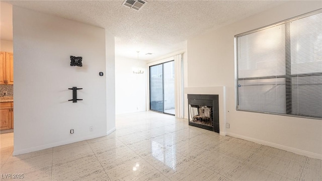 unfurnished living room featuring baseboards, a fireplace, and a textured ceiling