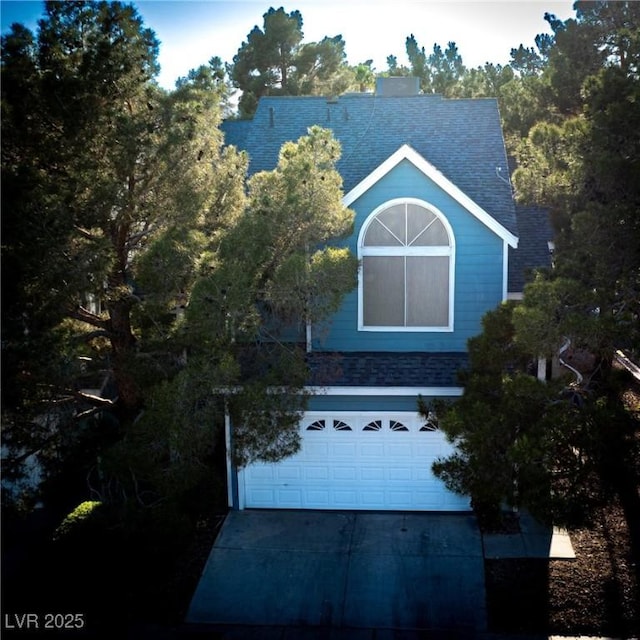 view of front facade with roof with shingles, a garage, and driveway