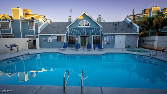 pool at dusk featuring fence, a community pool, and a hot tub