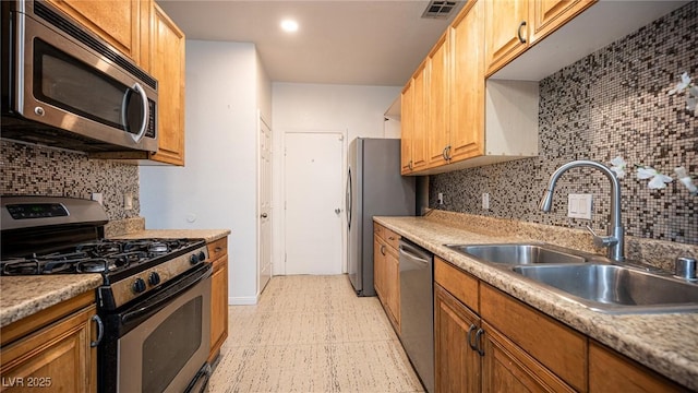 kitchen featuring appliances with stainless steel finishes, a sink, light floors, decorative backsplash, and recessed lighting