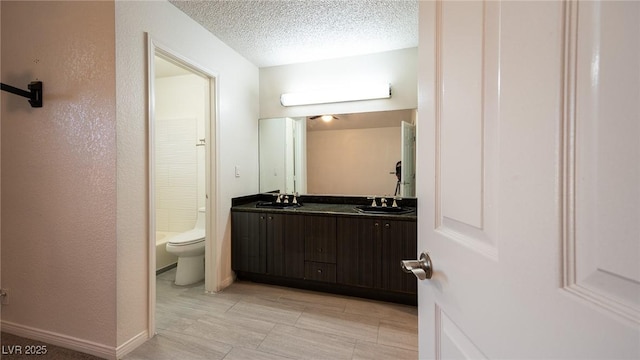 full bath featuring double vanity, a textured ceiling, and toilet