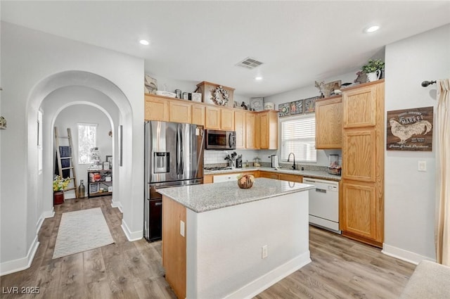 kitchen with stainless steel appliances, a sink, a center island, light wood-type flooring, and recessed lighting