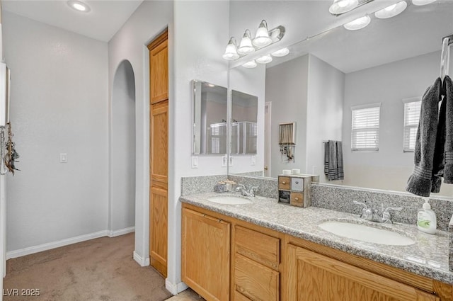 full bathroom featuring double vanity and baseboards