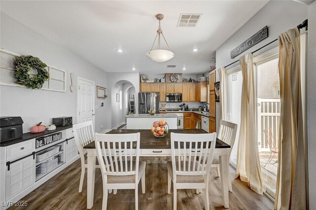 dining area with arched walkways, wood finished floors, and recessed lighting