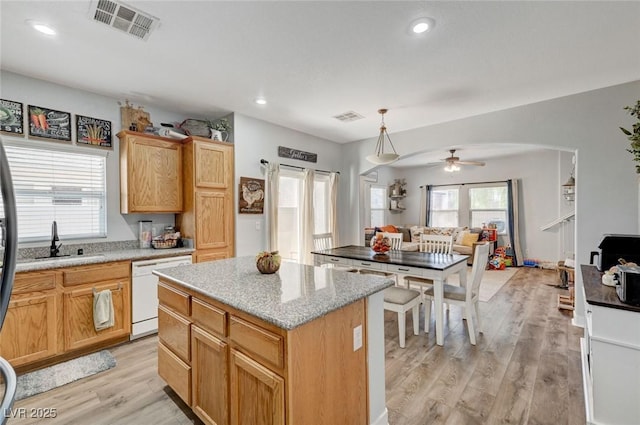 kitchen with white dishwasher, a kitchen island, light wood-type flooring, ceiling fan, and open floor plan