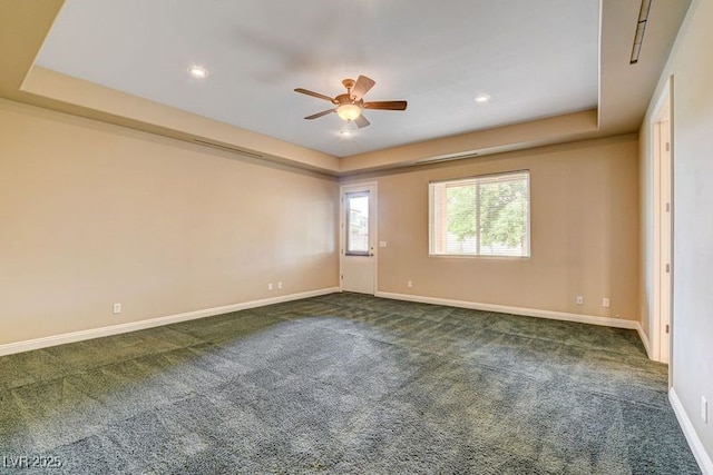 unfurnished room with a ceiling fan, a raised ceiling, dark carpet, baseboards, and recessed lighting