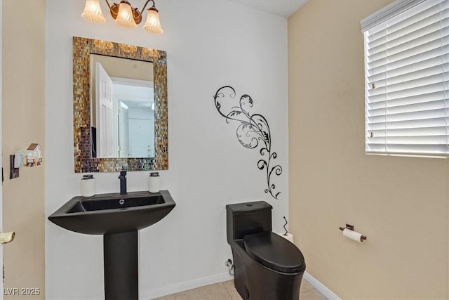 half bath featuring baseboards, a chandelier, toilet, and a sink