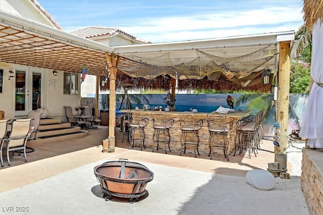 view of patio / terrace with an outdoor fire pit, exterior bar, and french doors