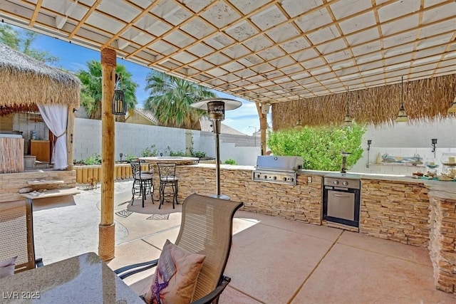 view of patio with grilling area, an outdoor bar, area for grilling, and fence