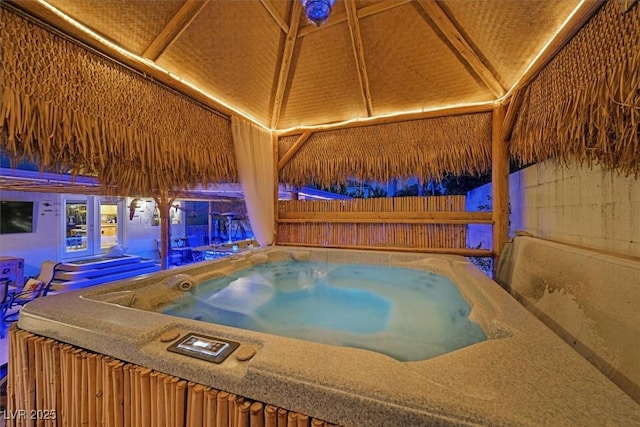 view of pool with a hot tub, fence, and a gazebo