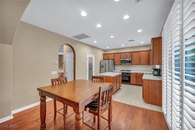 9893 Santa Ponsa Ct, Las Vegas, NV 89178 - kitchen featuring stainless steel appliances, arched walkways, a center island, light countertops, and brown cabinets