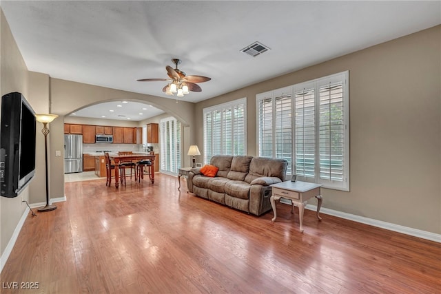 9893 Santa Ponsa Ct, Las Vegas, NV 89178 - living area with arched walkways, ceiling fan, light wood-type flooring, and baseboards