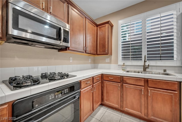 9893 Santa Ponsa Ct, Las Vegas, NV 89178 - kitchen featuring stainless steel microwave, oven, a sink, brown cabinetry, and black gas stovetop