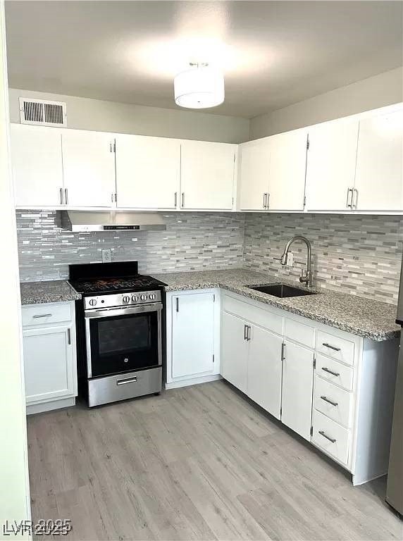 212 Orland St Unit 22, Las Vegas, NV 89107 - kitchen featuring stainless steel range with gas stovetop, a sink, under cabinet range hood, and white cabinetry