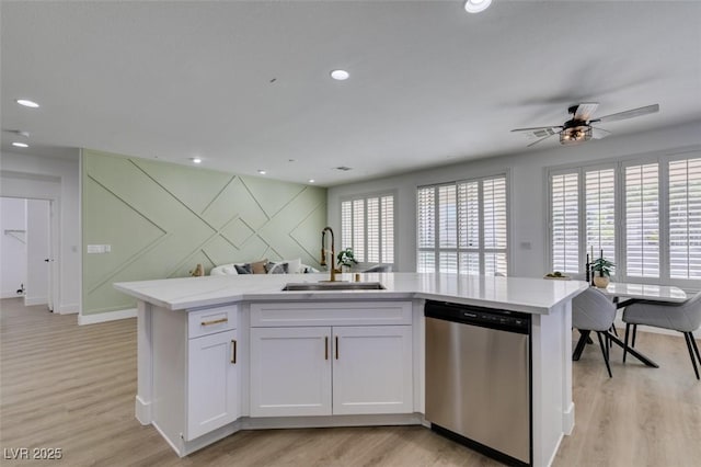 10389 Felice Ave, Las Vegas, NV 89135 - kitchen featuring stainless steel dishwasher, a sink, open floor plan, light wood-type flooring, and white cabinetry