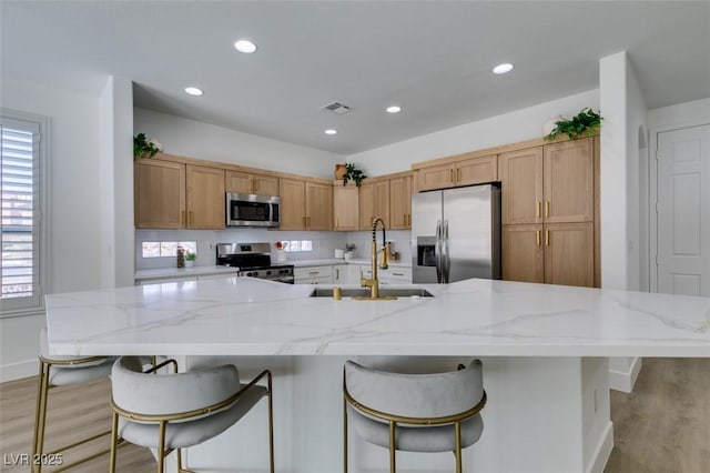 10389 Felice Ave, Las Vegas, NV 89135 - kitchen with appliances with stainless steel finishes, a sink, light wood-style floors, recessed lighting, and light stone counters