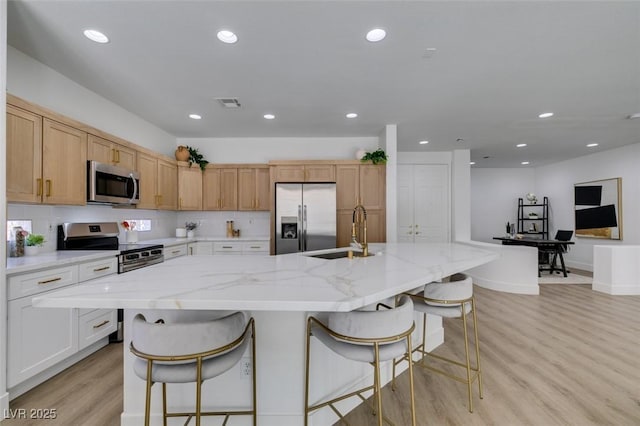 10389 Felice Ave, Las Vegas, NV 89135 - kitchen with appliances with stainless steel finishes, a sink, light wood-type flooring, recessed lighting, and a kitchen bar