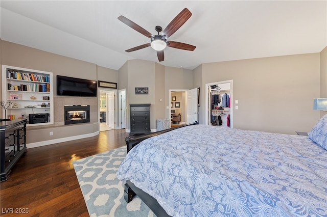 2113 Waterbury Ln, Las Vegas, NV 89134 - bedroom featuring vaulted ceiling, wood finished floors, a multi sided fireplace, a walk in closet, and a ceiling fan