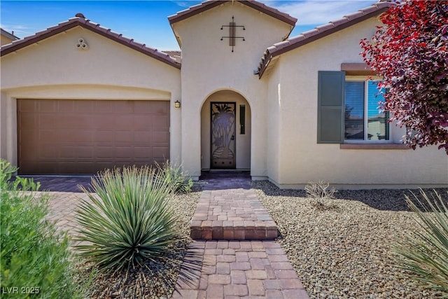 mediterranean / spanish-style home with stucco siding, an attached garage, and a tiled roof