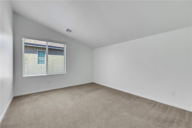 carpeted spare room with vaulted ceiling and baseboards