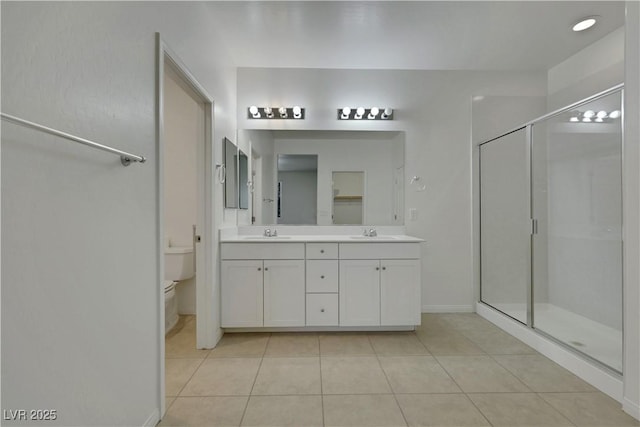 bathroom with a stall shower, toilet, tile patterned floors, double vanity, and baseboards