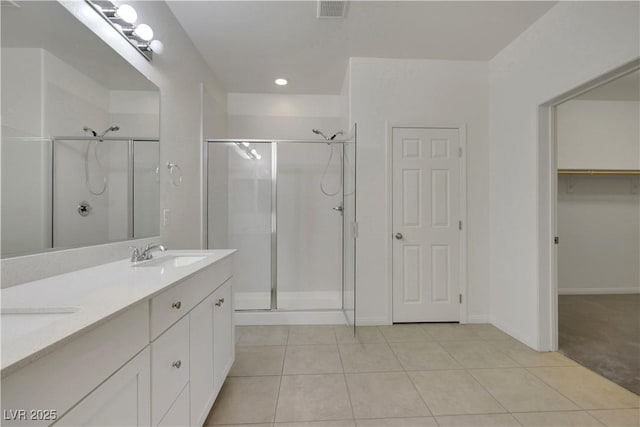 full bathroom with a stall shower, tile patterned floors, double vanity, and baseboards