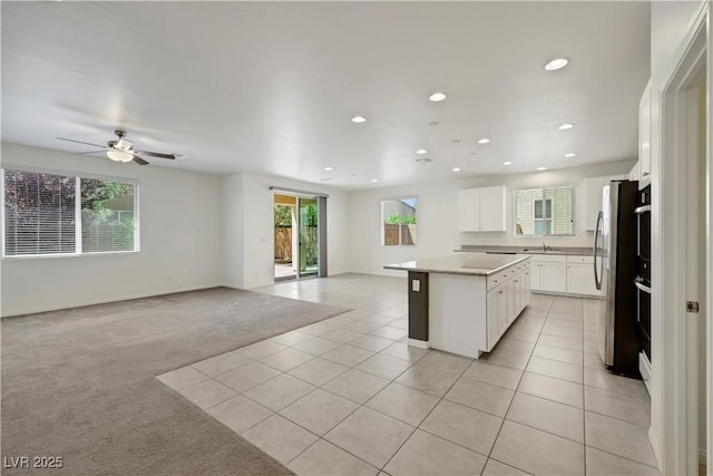 kitchen with open floor plan, a center island, freestanding refrigerator, light tile patterned floors, and recessed lighting