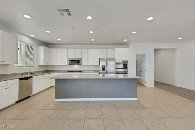 kitchen featuring stainless steel appliances, a kitchen island, recessed lighting, a sink, and white cabinetry