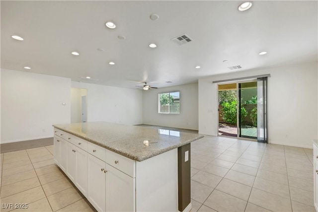 kitchen featuring light tile patterned flooring, a kitchen island, a ceiling fan, open floor plan, and white cabinetry