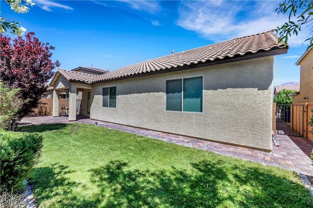 rear view of property featuring stucco siding, a tiled roof, and a patio area