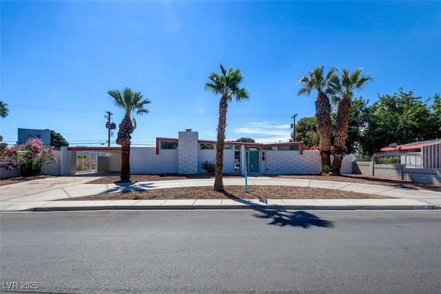 mid-century modern home featuring fence and driveway