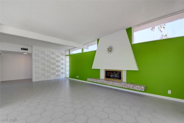 unfurnished living room with a glass covered fireplace and baseboards