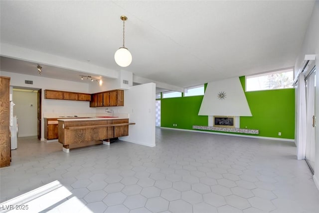 kitchen with open floor plan, brown cabinetry, plenty of natural light, and a sink