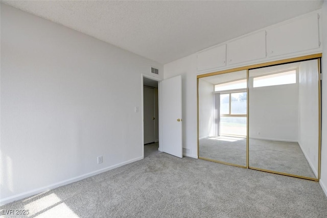 unfurnished bedroom featuring light colored carpet, baseboards, and a closet