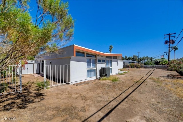 view of property exterior with a storage shed, cooling unit, an outdoor structure, and fence