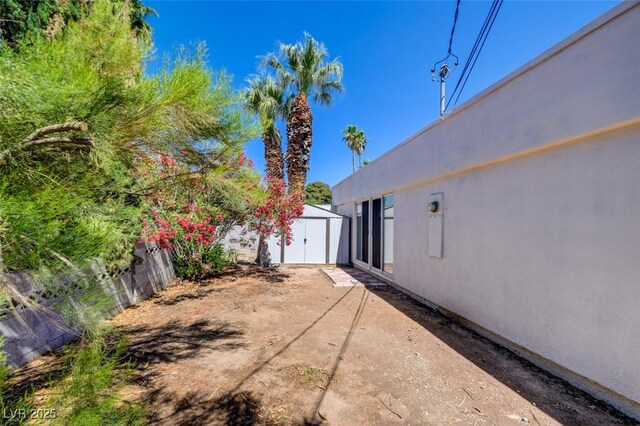 view of yard featuring a storage unit, an outdoor structure, and a patio