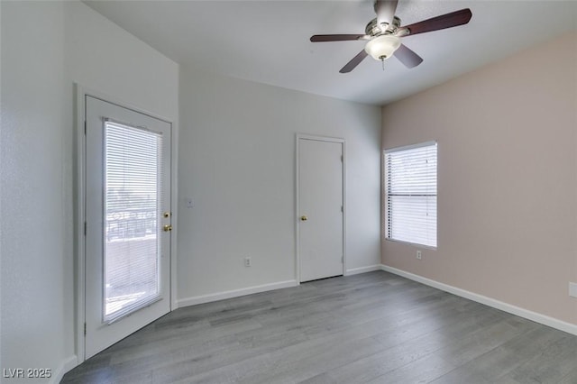 empty room featuring a ceiling fan, wood finished floors, and baseboards