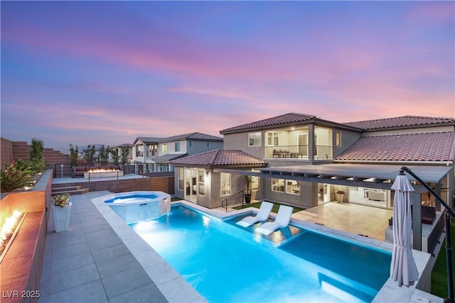 4505 Amazing View St, Las Vegas, NV 89129 - back of property at dusk featuring a pool with connected hot tub, a tiled roof, a fenced backyard, a patio area, and stucco siding