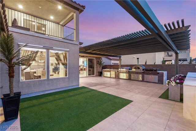 4505 Amazing View St, Las Vegas, NV 89129 - yard at dusk with an outdoor kitchen, a balcony, a patio, and a pergola