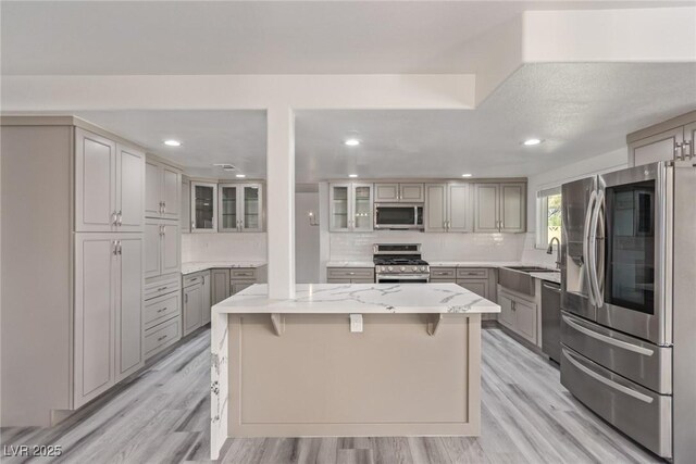 326 Fuente Dr, Henderson, NV 89014 - kitchen with stainless steel appliances, gray cabinets, a sink, backsplash, and light wood-style flooring