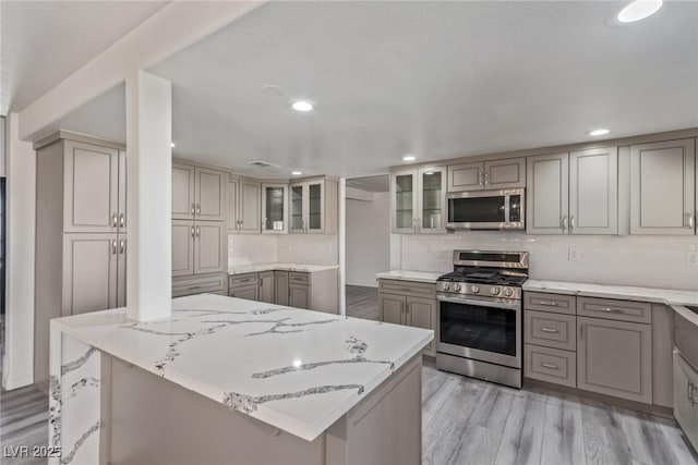 326 Fuente Dr, Henderson, NV 89014 - kitchen featuring stainless steel appliances, gray cabinetry, light stone counters, recessed lighting, and light wood finished floors