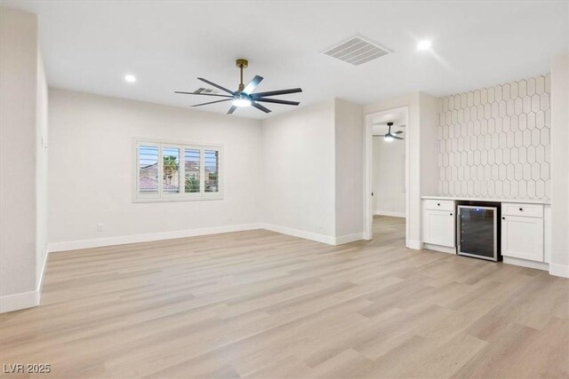 unfurnished living room with beverage cooler, light wood-type flooring, baseboards, a ceiling fan, and recessed lighting