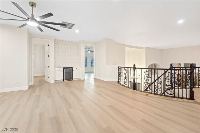 unfurnished room featuring a ceiling fan, light wood finished floors, wine cooler, baseboards, and recessed lighting