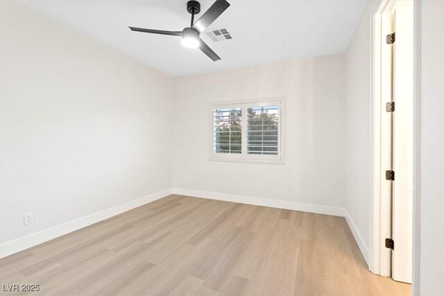 spare room with light wood-type flooring, a ceiling fan, and baseboards