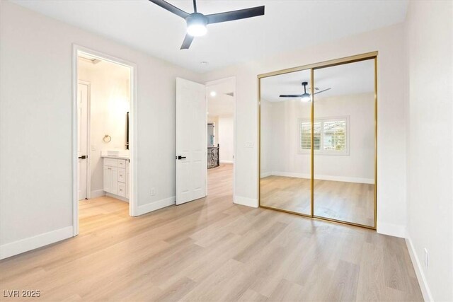 unfurnished bedroom with light wood-style flooring, a closet, baseboards, connected bathroom, and ceiling fan