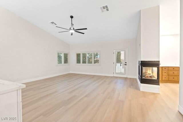 unfurnished living room with light wood finished floors, ceiling fan, a multi sided fireplace, baseboards, and high vaulted ceiling