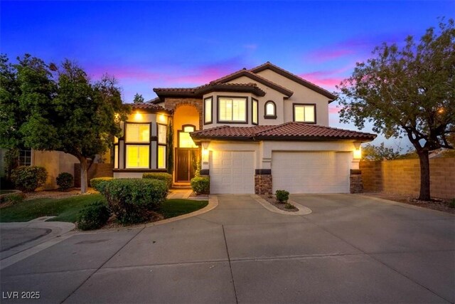 mediterranean / spanish-style house featuring concrete driveway, fence, stucco siding, a tile roof, and a garage